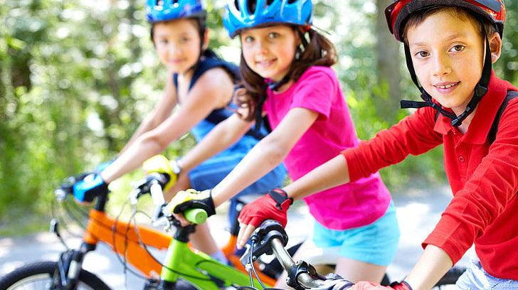 three kids wearing helmets on bikes