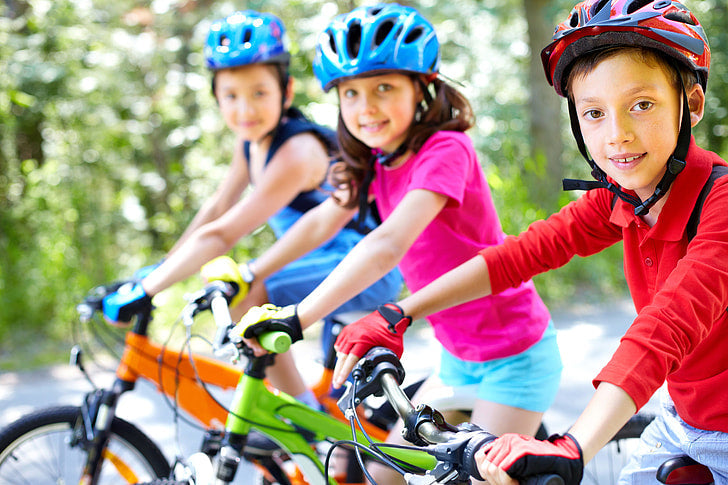 three kids wearing helmets on bikes